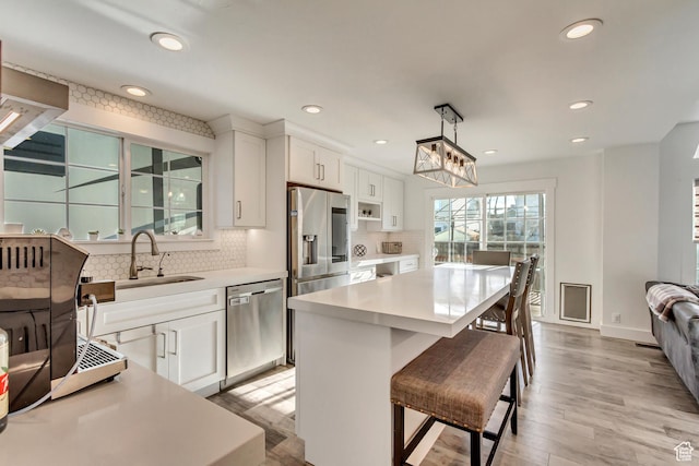kitchen featuring appliances with stainless steel finishes, a sink, light wood-style floors, tasteful backsplash, and recessed lighting
