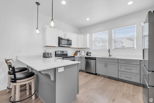 13963 S Wide Ridge Way Unit 1121, Herriman, UT 84096 - kitchen featuring stainless steel appliances, sink, pendant lighting, white cabinetry, and a breakfast bar area