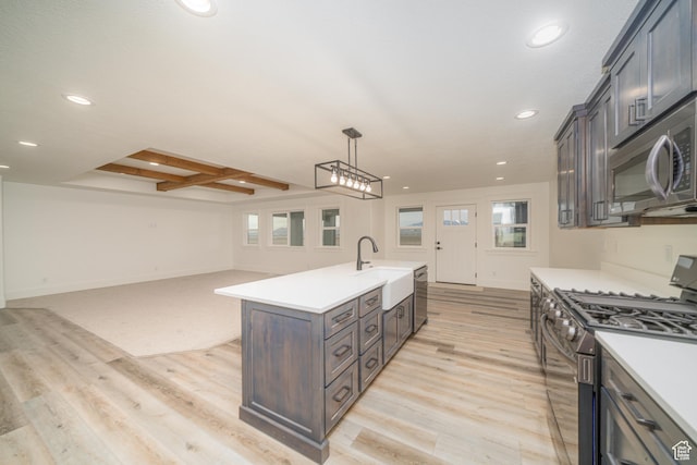 kitchen with beamed ceiling, appliances with stainless steel finishes, light wood-type flooring, and decorative light fixtures