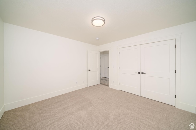 unfurnished bedroom with light colored carpet and a closet