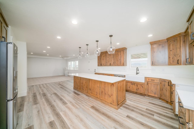 kitchen with a center island, sink, hanging light fixtures, stainless steel fridge with ice dispenser, and light hardwood / wood-style floors