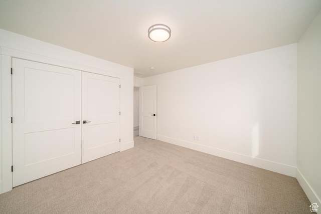 unfurnished bedroom featuring light carpet and a closet