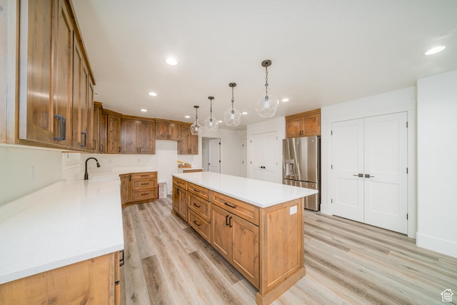 kitchen featuring sink, hanging light fixtures, light wood-type flooring, a kitchen island, and stainless steel fridge with ice dispenser