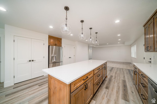 kitchen with pendant lighting, a kitchen island, light wood-type flooring, and appliances with stainless steel finishes