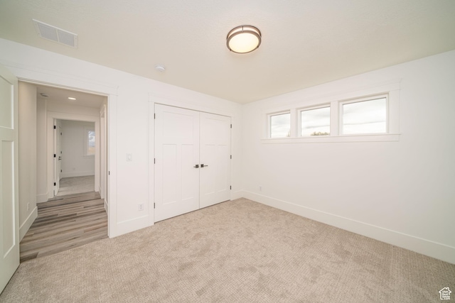 unfurnished bedroom with light carpet and a closet