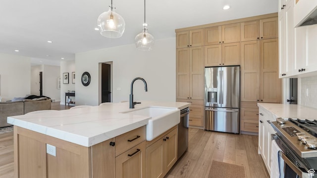 928 N Foxhunter Dr W, Farmington, UT 84025 - kitchen featuring stainless steel appliances, a sink, light brown cabinets, light wood-style flooring, and light stone countertops
