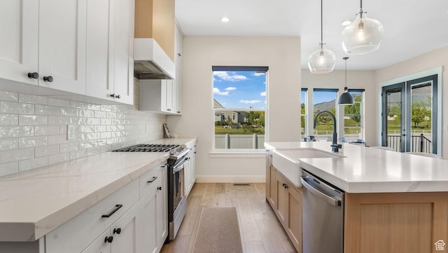 928 N Foxhunter Dr W, Farmington, UT 84025 - kitchen with appliances with stainless steel finishes, a sink, light wood-style flooring, backsplash, and a center island with sink