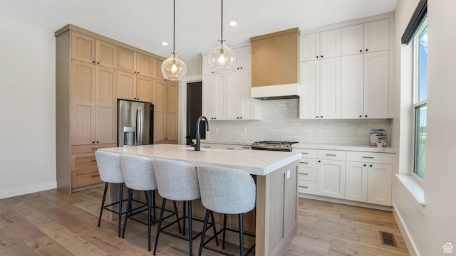 928 N Foxhunter Dr W, Farmington, UT 84025 - kitchen featuring stainless steel fridge, tasteful backsplash, a kitchen breakfast bar, light wood-type flooring, and recessed lighting