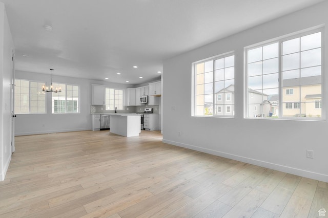 6627 W Spring Snow Ln, Herriman, UT 84096 - unfurnished living room with a chandelier, baseboards, light wood-style flooring, recessed lighting, and a sink