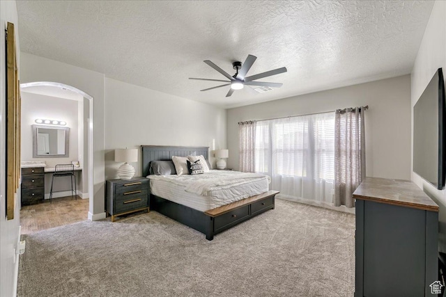 3459 S 2960 E, St George, UT 84790 - carpeted bedroom with arched walkways, a textured ceiling, visible vents, a ceiling fan, and ensuite bath