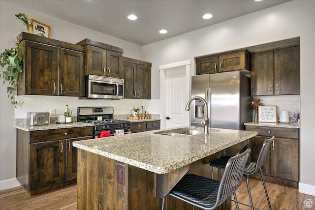 3459 S 2960 E, St George, UT 84790 - kitchen featuring stainless steel appliances, a sink, dark brown cabinetry, decorative backsplash, and wood finished floors
