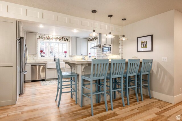 2760 E Spring Creek Rd, Holladay, UT 84117 - kitchen featuring a kitchen bar, appliances with stainless steel finishes, backsplash, hanging light fixtures, and sink