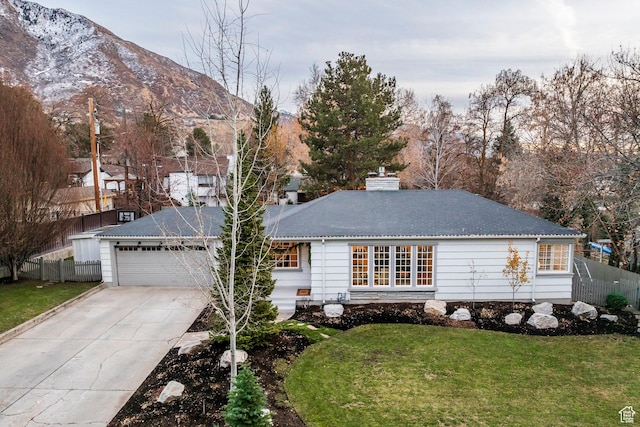 ranch-style house featuring a mountain view, a front yard, and a garage