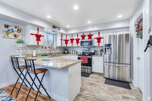 685 E Bullrush Pkwy E, Lehi, UT 84043 - kitchen with kitchen peninsula, stainless steel appliances, sink, white cabinetry, and a breakfast bar area