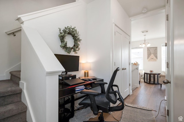 home office with light wood finished floors and a notable chandelier