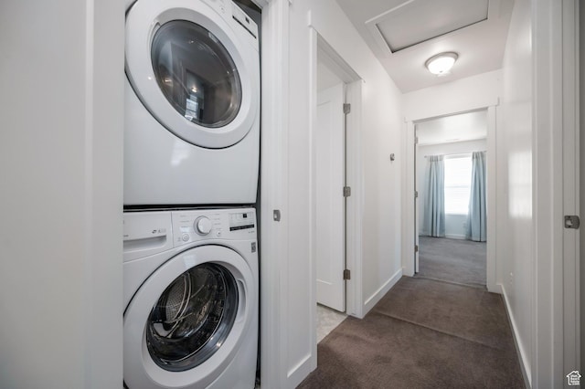 clothes washing area with attic access, stacked washing maching and dryer, carpet flooring, and baseboards