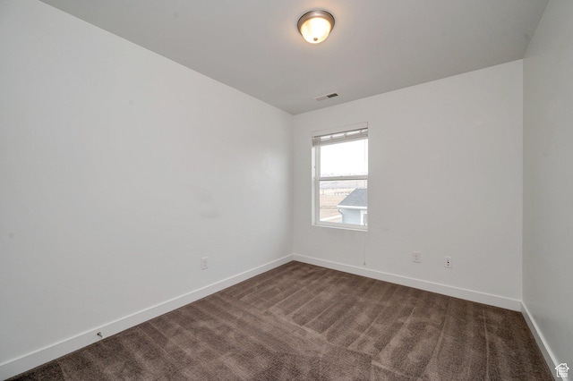 unfurnished room with dark colored carpet, visible vents, and baseboards