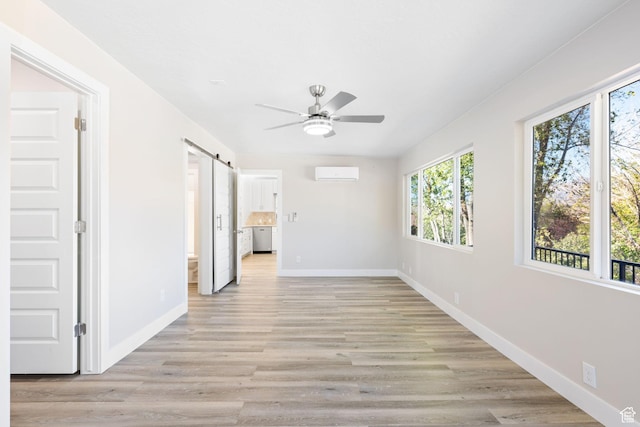 hall featuring a wall mounted air conditioner, a barn door, and light hardwood / wood-style floors