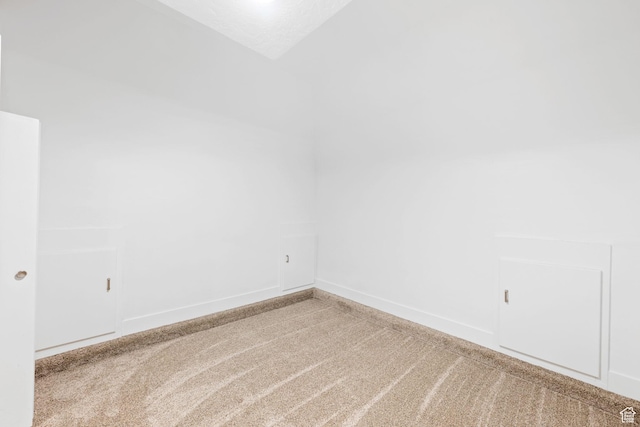 carpeted empty room featuring a textured ceiling and lofted ceiling