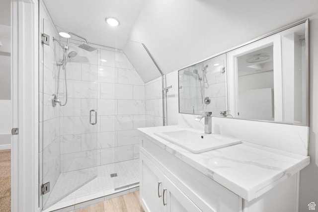 bathroom with vanity, hardwood / wood-style flooring, walk in shower, and lofted ceiling