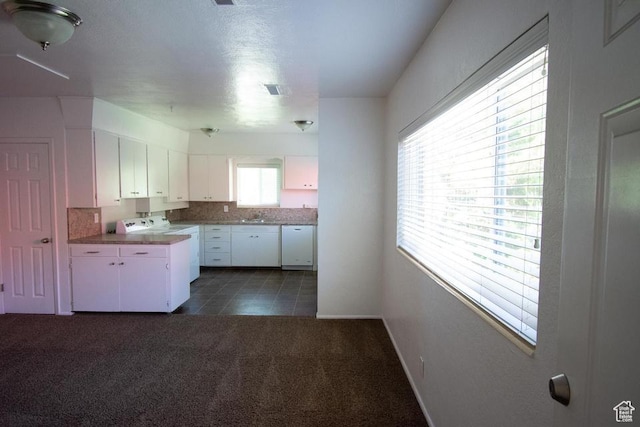 kitchen featuring dark carpet, white cabinets, white dishwasher, sink, and range