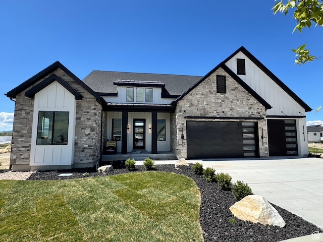 modern farmhouse with stone siding, a porch, a front yard, and board and batten siding