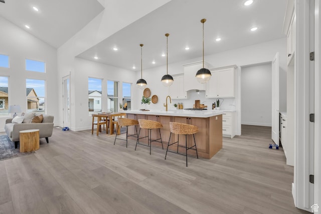 kitchen featuring light wood-type flooring, a breakfast bar area, baseboards, light countertops, and recessed lighting