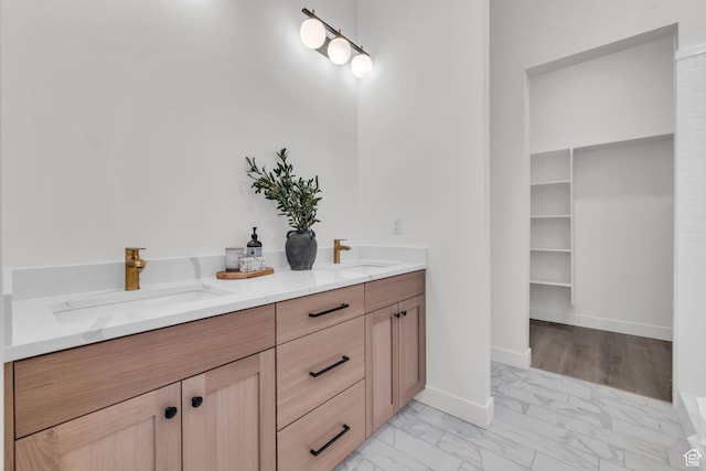 bathroom featuring marble finish flooring, double vanity, and baseboards