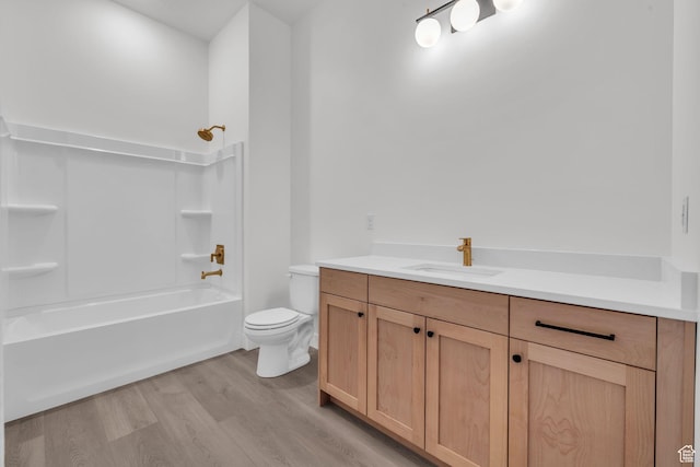 full bath with toilet, wood finished floors, vanity, and shower / tub combination