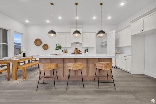 kitchen featuring light wood-style floors, white cabinetry, light countertops, an island with sink, and recessed lighting