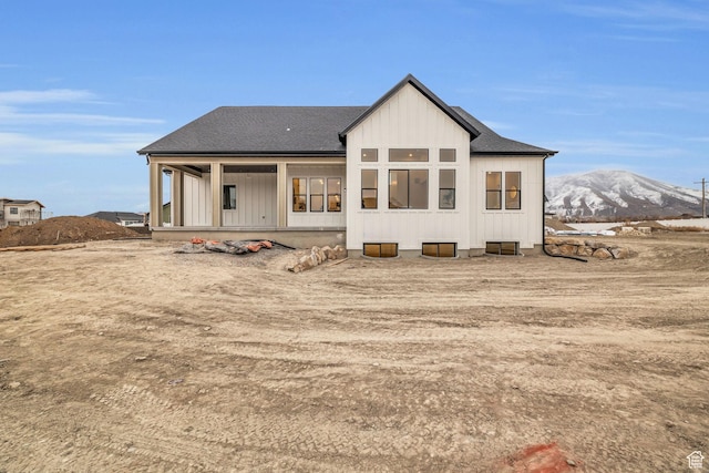 back of property with a mountain view, roof with shingles, a porch, and board and batten siding