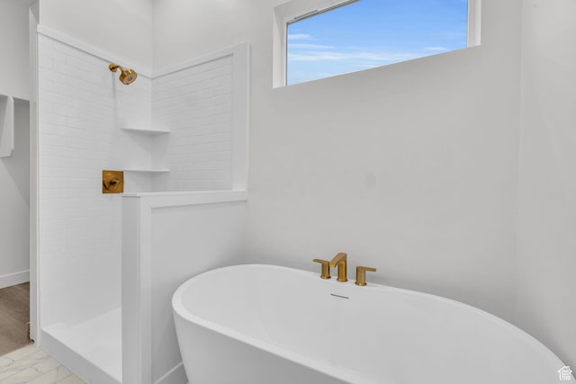 full bathroom with tiled shower, a freestanding bath, and marble look tile flooring