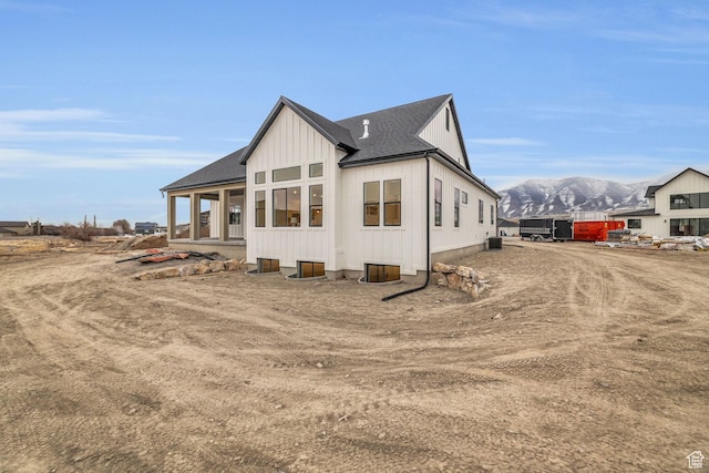 back of property with a mountain view and a shingled roof