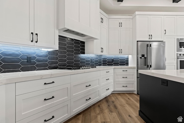 1539 W 2130th Cir S, St George, UT 84770 - kitchen featuring stainless steel appliances, light stone counters, light hardwood / wood-style flooring, backsplash, and white cabinets