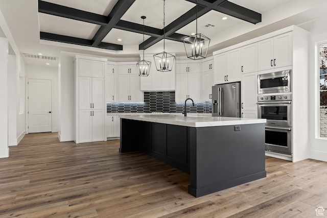 1539 W 2130th Cir S, St George, UT 84770 - kitchen with appliances with stainless steel finishes, tasteful backsplash, a kitchen island with sink, hardwood / wood-style flooring, and white cabinetry