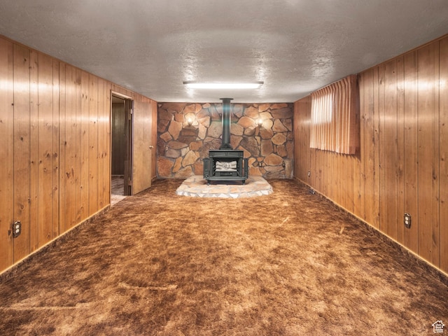 5304 W 20400 N, Plymouth, UT 84330 - unfurnished living room featuring carpet, wood walls, a wood stove, and a textured ceiling