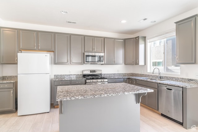 kitchen with gray cabinetry, a kitchen island, sink, and appliances with stainless steel finishes