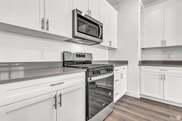 1056 E 1930 S Unit 420, Heber City, UT 84032 - kitchen with appliances with stainless steel finishes, white cabinetry, light wood-style flooring, and dark countertops