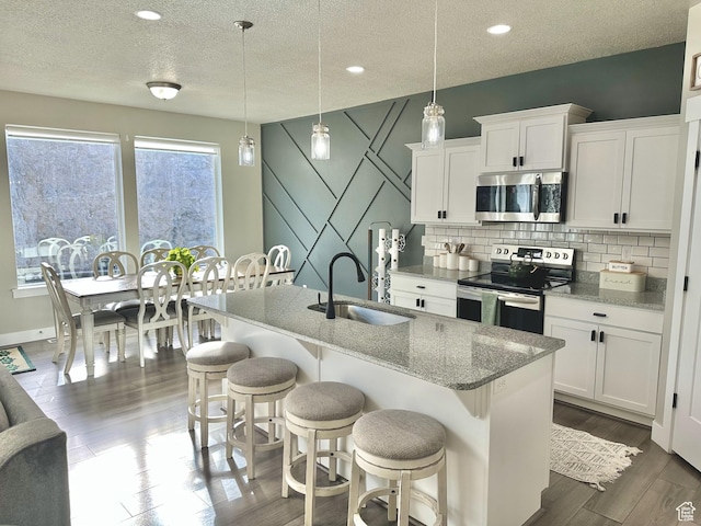 6057 W Herriman View Way S, Herriman, UT 84096 - kitchen featuring a kitchen breakfast bar, stainless steel appliances, a sink, a center island with sink, and decorative backsplash