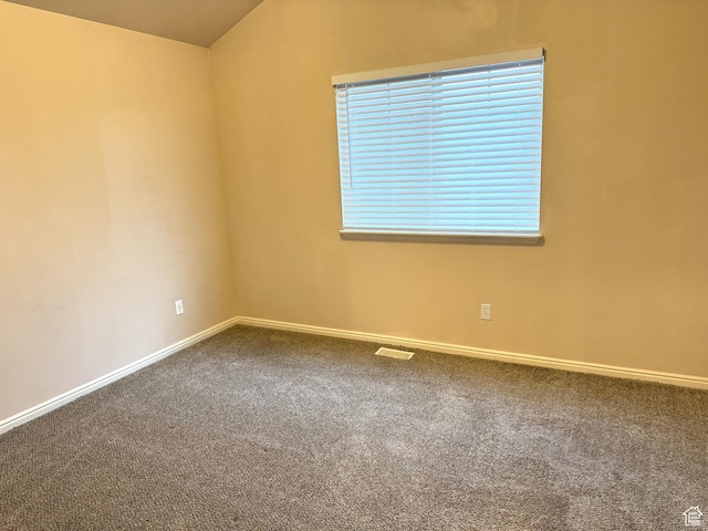 spare room featuring carpet and vaulted ceiling