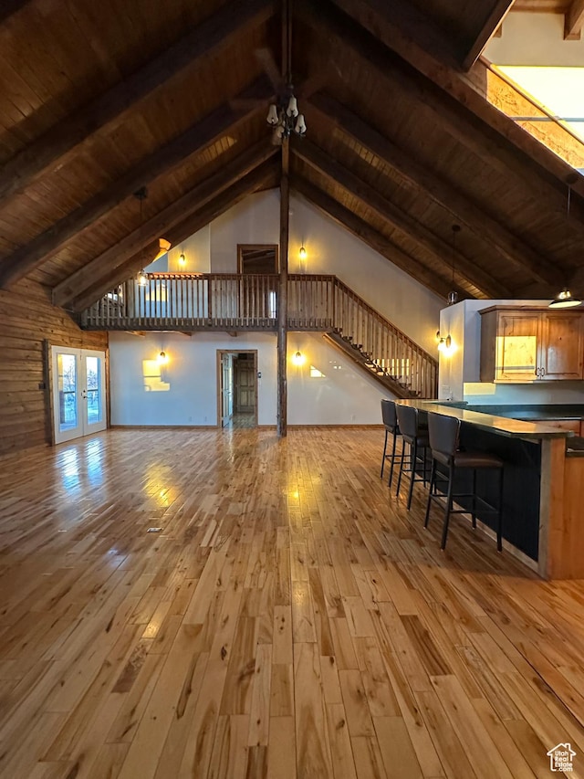 unfurnished living room with french doors, wooden ceiling, high vaulted ceiling, beamed ceiling, and light hardwood / wood-style floors