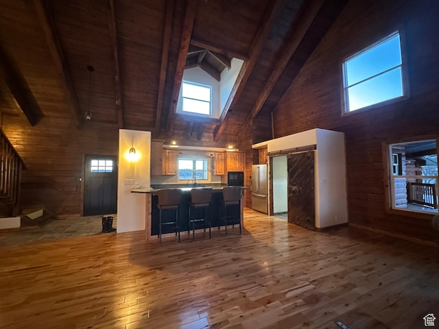 kitchen featuring high vaulted ceiling, a kitchen breakfast bar, beam ceiling, kitchen peninsula, and wood ceiling