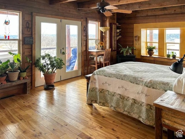 bedroom with ceiling fan, french doors, access to outside, wooden walls, and light wood-type flooring