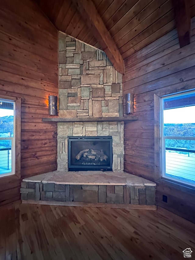 room details featuring a stone fireplace, beamed ceiling, wood walls, wood-type flooring, and wood ceiling