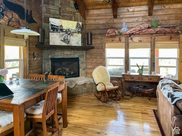 dining area with a fireplace, light wood-type flooring, lofted ceiling with beams, and a wealth of natural light
