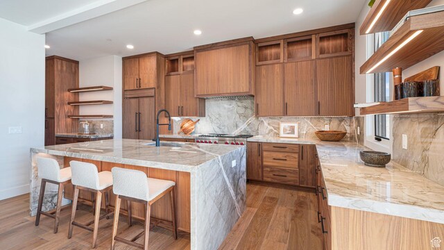 2072 E Copper Belt Dr, Heber City, UT 84032 - kitchen with light wood-type flooring, backsplash, sink, paneled built in fridge, and an island with sink