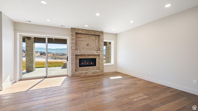2072 E Copper Belt Dr, Heber City, UT 84032 - unfurnished living room featuring a stone fireplace, a wealth of natural light, and light hardwood / wood-style flooring