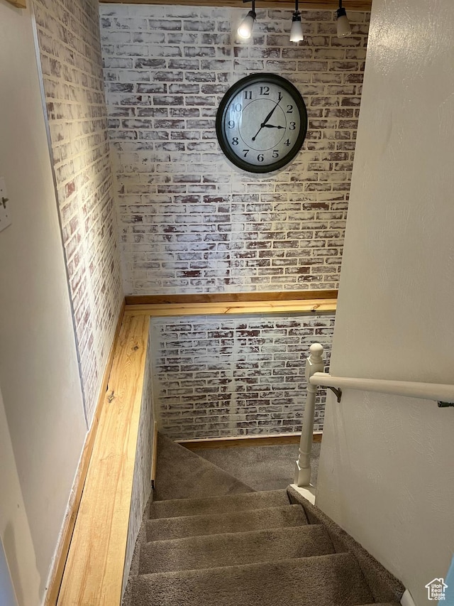 staircase featuring brick wall and carpet floors