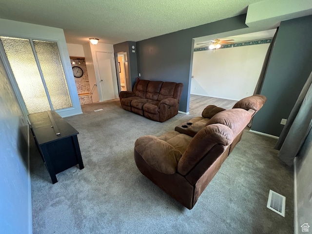 living area with a textured ceiling, carpet flooring, visible vents, and a ceiling fan