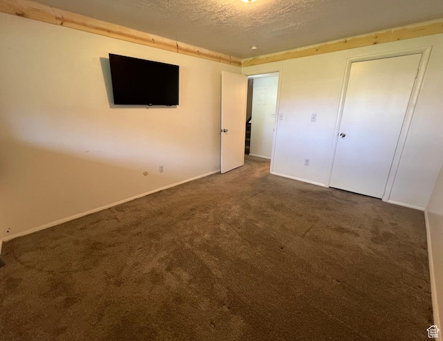 unfurnished bedroom featuring baseboards, a textured ceiling, and carpet